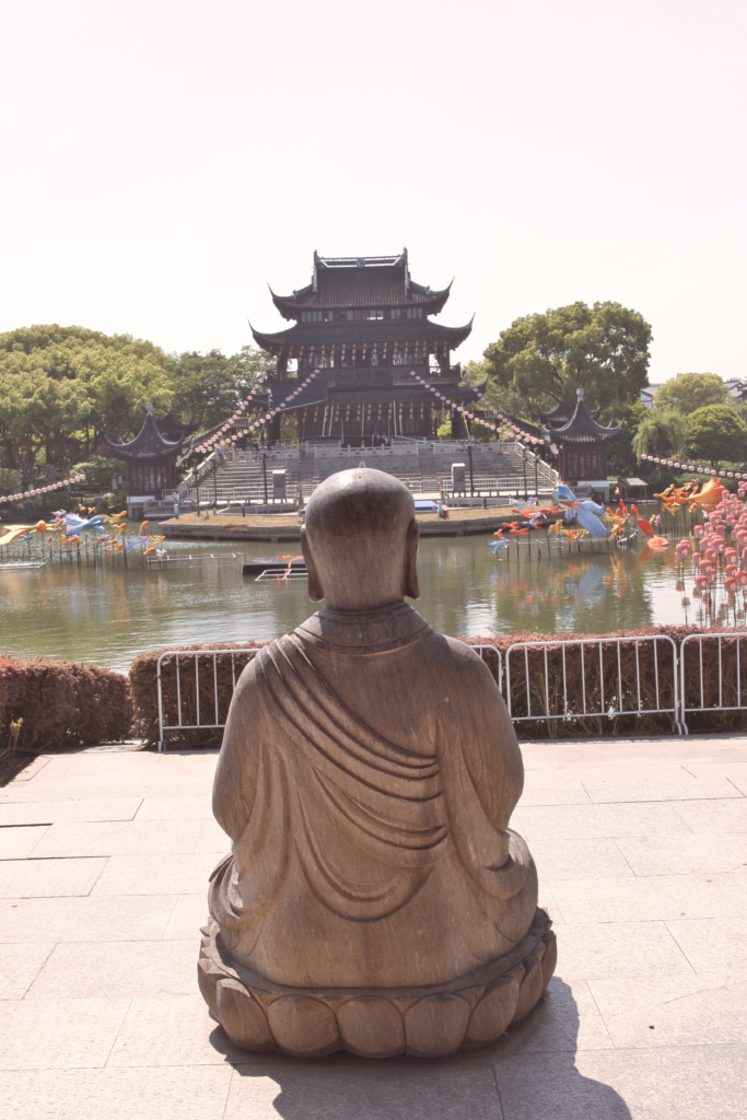 Plaza en Suzhou en jardines con castillo tradicional al fondo y estatua de Buda