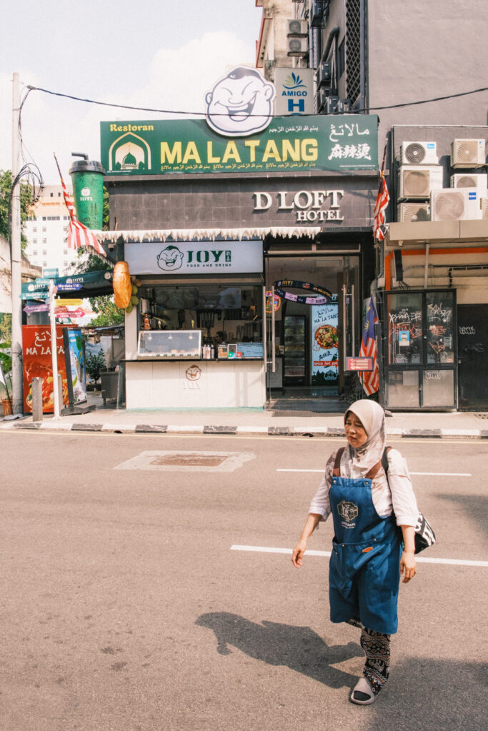 Mujer con hiyab caminando por delante de un restorán en malasia Kuala Lumpur